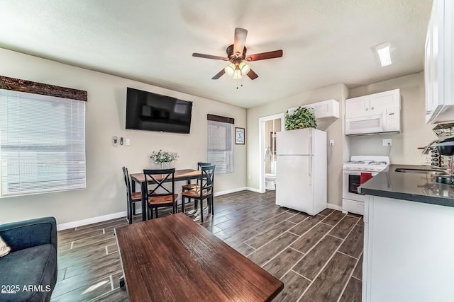 kitchen with wood tiled floor, white appliances, dark countertops, and white cabinets