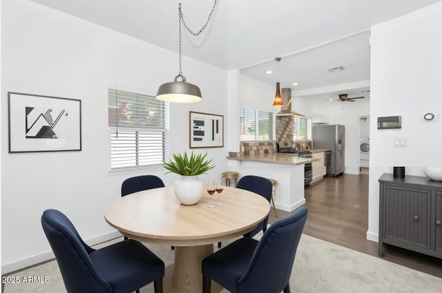 dining room featuring baseboards, wood finished floors, washer / dryer, and a ceiling fan
