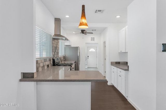 kitchen featuring a ceiling fan, white cabinets, visible vents, and wall chimney exhaust hood