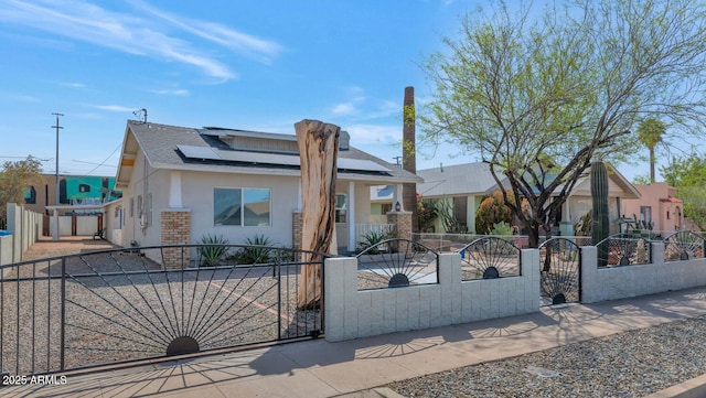 view of front of home with a gate, solar panels, brick siding, a fenced front yard, and stucco siding