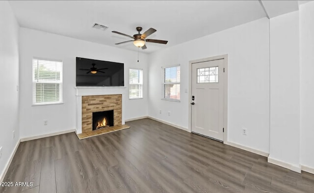 unfurnished living room featuring a wealth of natural light, visible vents, a tiled fireplace, and wood finished floors