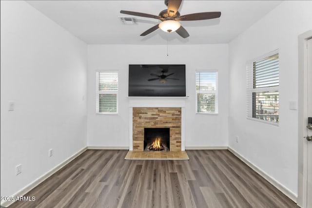 unfurnished living room with a warm lit fireplace, wood finished floors, plenty of natural light, and visible vents