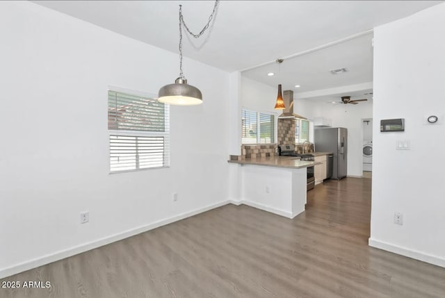 kitchen with a peninsula, baseboards, wood finished floors, stainless steel appliances, and ventilation hood