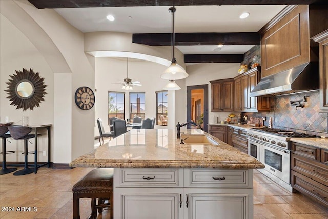 kitchen featuring a large island with sink, sink, a kitchen bar, and double oven range