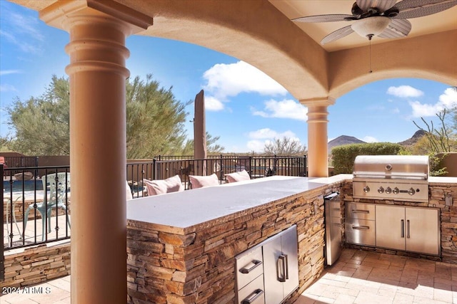 view of patio with area for grilling, ceiling fan, a mountain view, and a grill