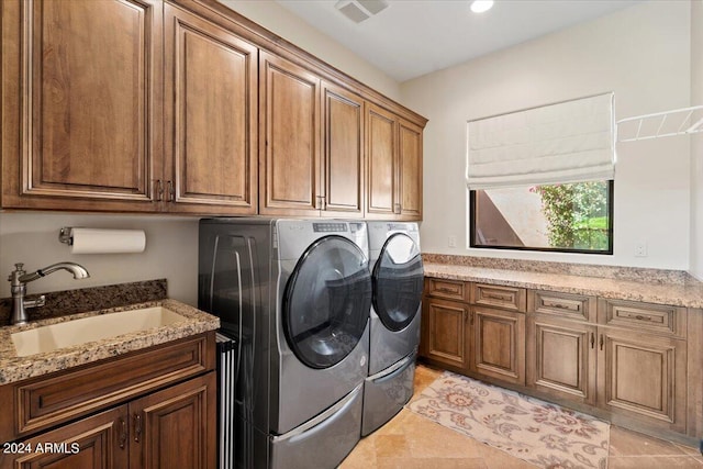 washroom with sink, washer and clothes dryer, light tile patterned floors, and cabinets