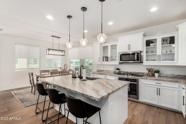 1250 N Abbey Ln Unit 206, Chandler, AZ 85226 - kitchen with appliances with stainless steel finishes, white cabinets, light stone counters, a kitchen bar, and hanging light fixtures