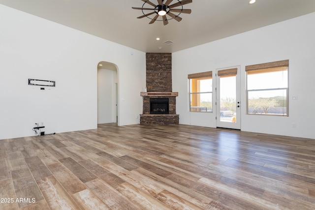 unfurnished living room with ceiling fan, a fireplace, and light hardwood / wood-style flooring