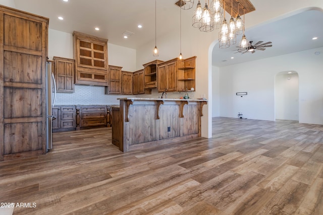 kitchen with pendant lighting, hardwood / wood-style flooring, a breakfast bar area, backsplash, and kitchen peninsula