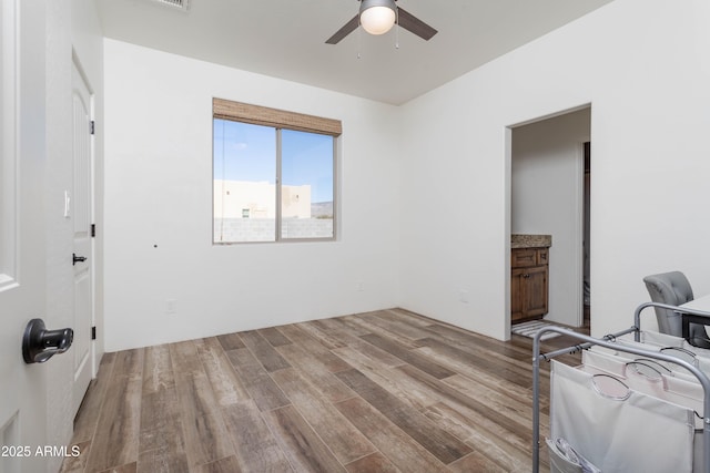 bedroom with ceiling fan, ensuite bathroom, and light wood-type flooring