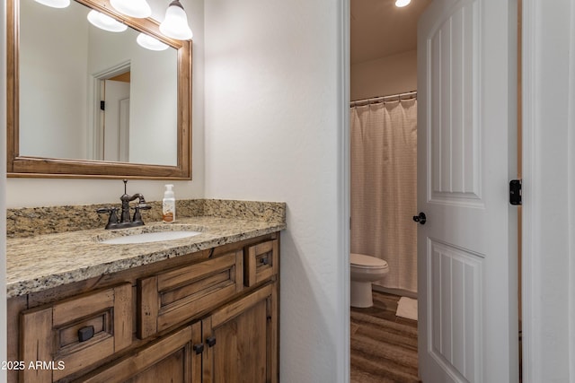 bathroom featuring wood-type flooring, walk in shower, vanity, and toilet