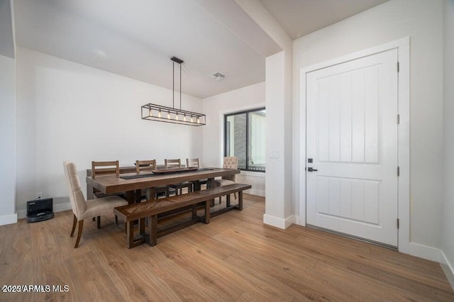 dining space with light wood finished floors, baseboards, and visible vents