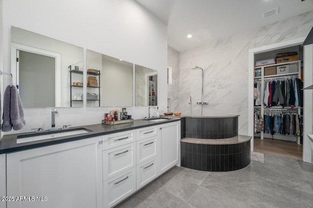 bathroom with double vanity, a spacious closet, visible vents, and a sink