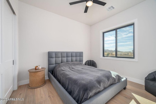 bedroom featuring baseboards, visible vents, ceiling fan, and wood finished floors