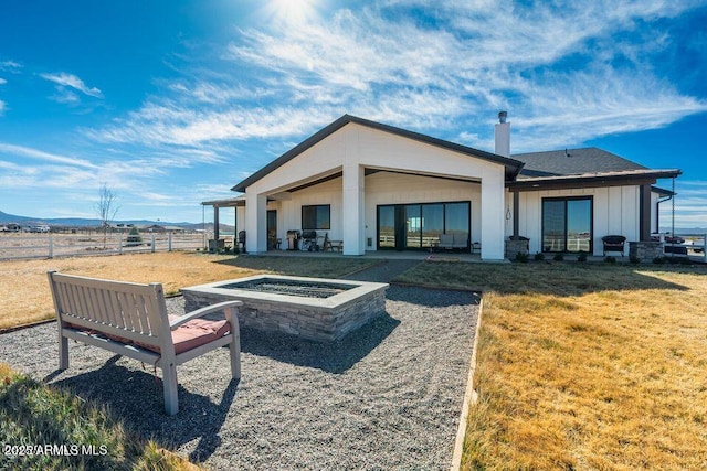 back of house with a yard, a patio, board and batten siding, an outdoor fire pit, and fence