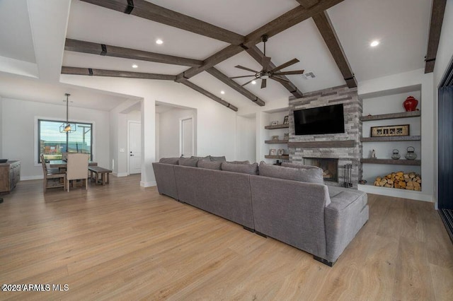 living room featuring ceiling fan, a stone fireplace, lofted ceiling with beams, and light wood-style floors