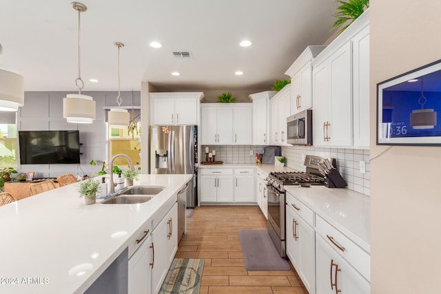 kitchen featuring white cabinetry, sink, pendant lighting, appliances with stainless steel finishes, and light wood-type flooring