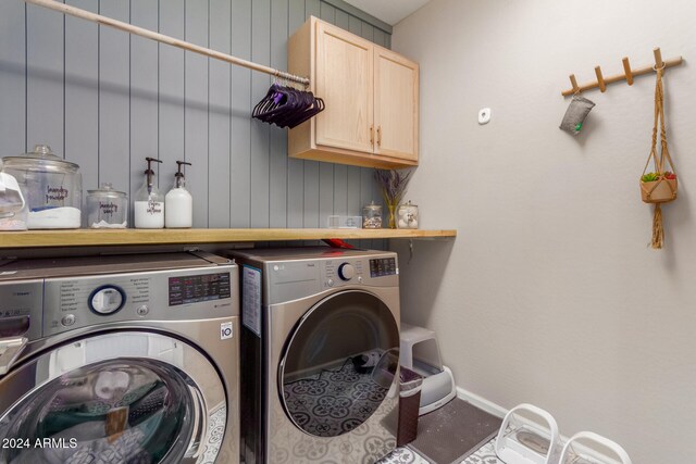 washroom featuring cabinets, washer and clothes dryer, and wood walls