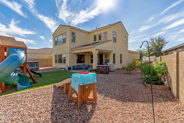 rear view of house featuring outdoor lounge area, a yard, and a playground