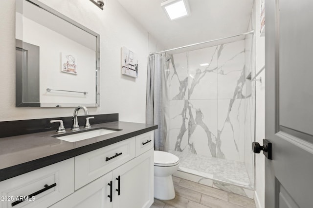 bathroom with a marble finish shower, toilet, vanity, and wood finished floors