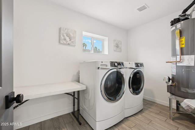 laundry room with washing machine and clothes dryer, light wood-style flooring, water heater, and baseboards