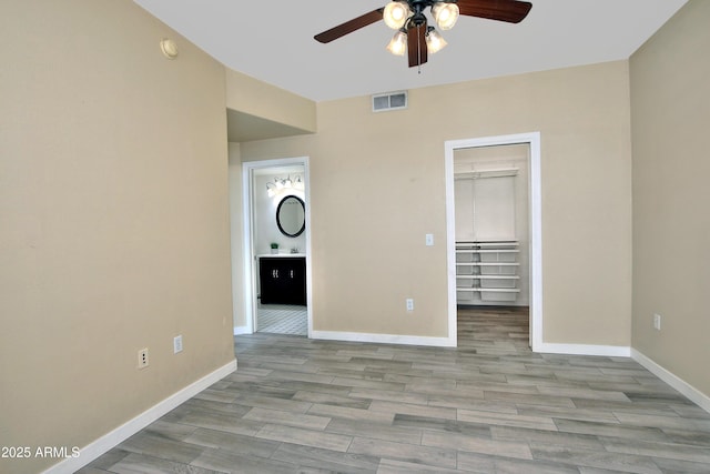 unfurnished bedroom featuring baseboards, a spacious closet, visible vents, and wood finished floors