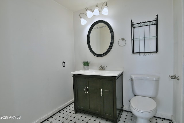 half bath featuring baseboards, vanity, toilet, and tile patterned floors