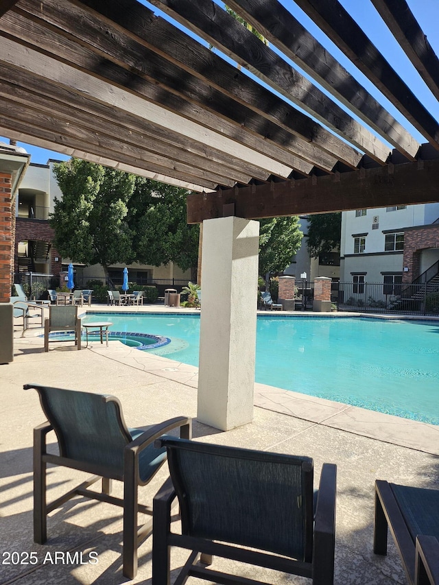 view of pool with a pool with connected hot tub, a patio area, fence, and a pergola