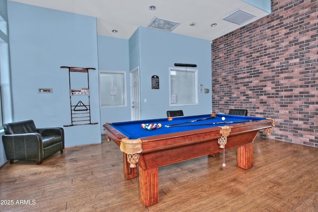 recreation room featuring billiards, brick wall, and hardwood / wood-style flooring