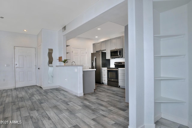 kitchen with a peninsula, visible vents, light countertops, appliances with stainless steel finishes, and light wood-type flooring