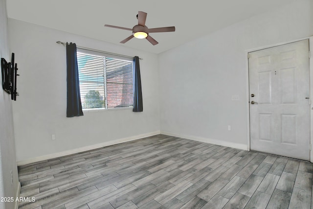 spare room featuring wood finished floors, a ceiling fan, and baseboards