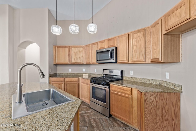 kitchen featuring appliances with stainless steel finishes, light stone counters, hanging light fixtures, and sink