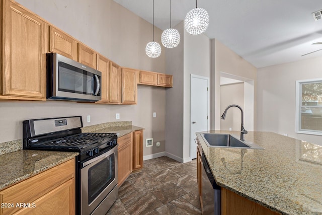 kitchen with appliances with stainless steel finishes, light stone counters, ceiling fan, sink, and pendant lighting