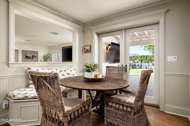 dining area featuring a wainscoted wall, visible vents, crown molding, and wood finished floors