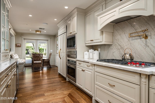 kitchen with visible vents, light stone counters, premium range hood, and appliances with stainless steel finishes