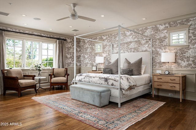 bedroom with a wainscoted wall, visible vents, multiple windows, and crown molding