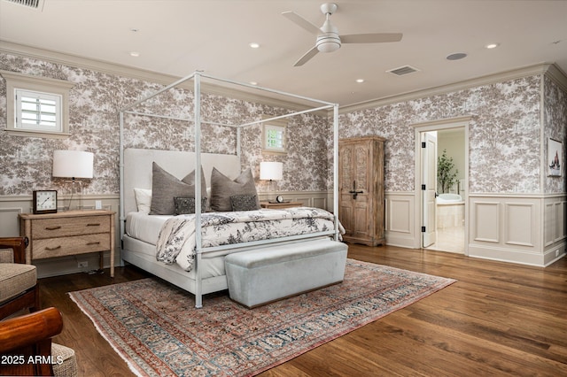 bedroom featuring wallpapered walls, crown molding, wood finished floors, and wainscoting