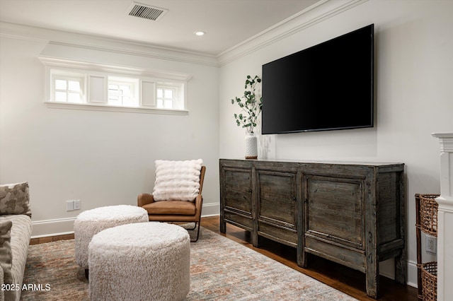 living area with baseboards, ornamental molding, visible vents, and wood finished floors