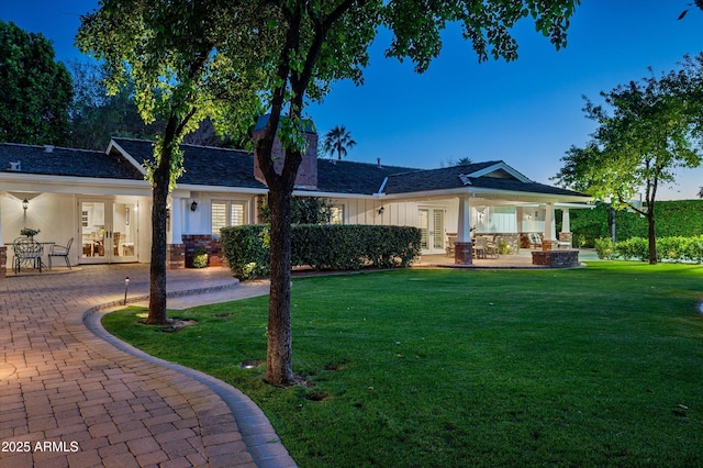 back of property featuring french doors, board and batten siding, a patio area, a yard, and a chimney