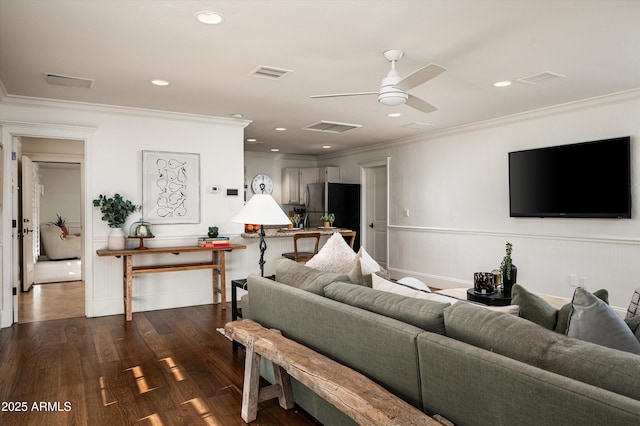 living area featuring dark wood-style flooring, ornamental molding, visible vents, and a ceiling fan