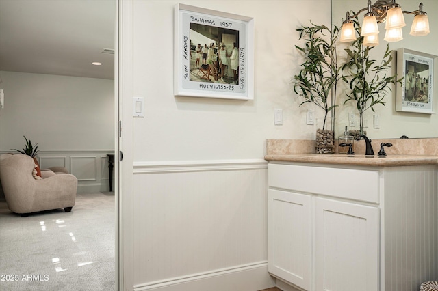 bathroom with a decorative wall, vanity, and wainscoting