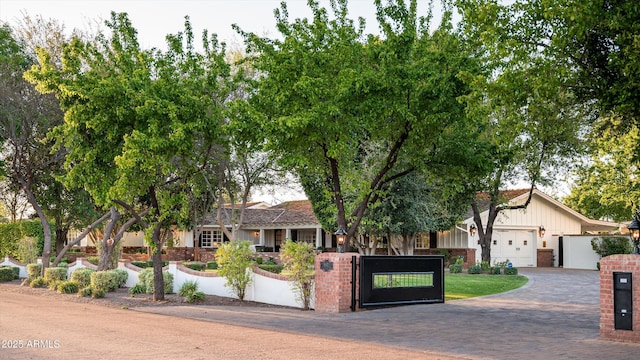 view of front facade featuring a gate, fence, decorative driveway, a garage, and board and batten siding
