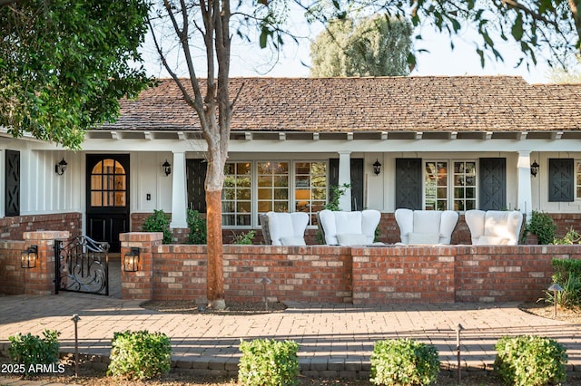 view of front facade with brick siding, a porch, and outdoor lounge area