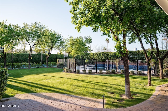 view of community featuring a swimming pool, fence, and a yard