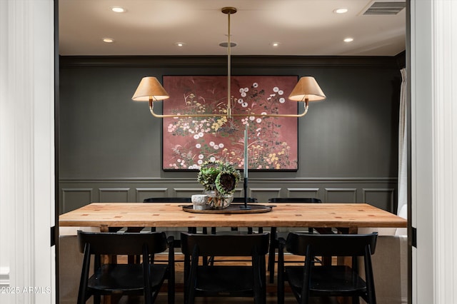 dining room featuring recessed lighting, visible vents, crown molding, and a decorative wall
