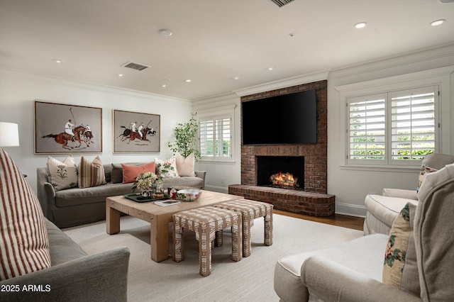 living area with crown molding, a fireplace, baseboards, visible vents, and light wood-style floors