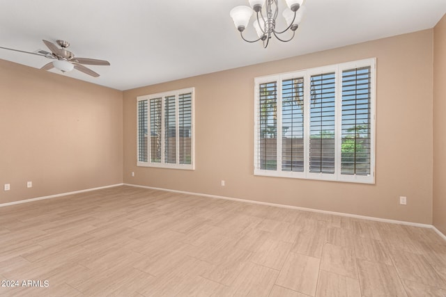 spare room with ceiling fan with notable chandelier