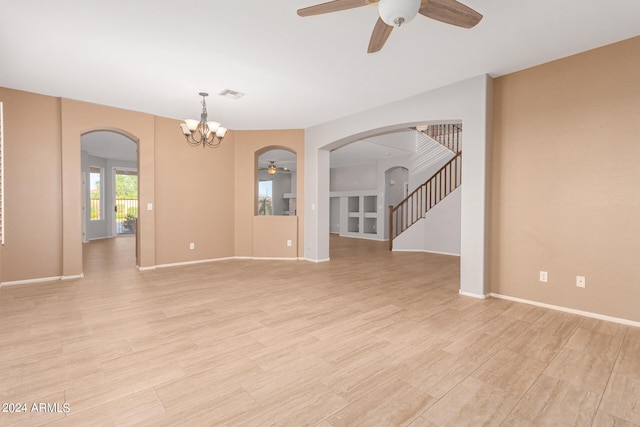 unfurnished living room with ceiling fan with notable chandelier and light hardwood / wood-style floors