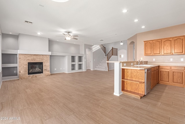 kitchen with built in features, ceiling fan, sink, kitchen peninsula, and stainless steel dishwasher