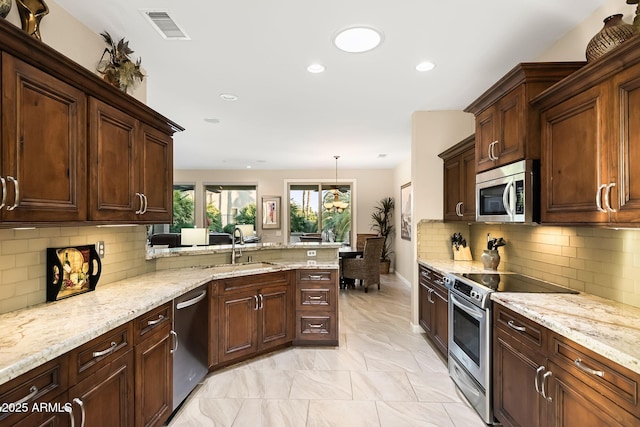 kitchen with visible vents, a sink, appliances with stainless steel finishes, a peninsula, and light stone countertops